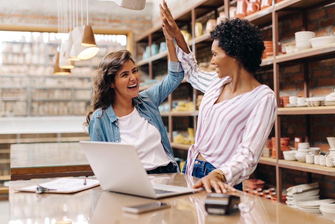 Self employed professionals celebrating while working on a laptop