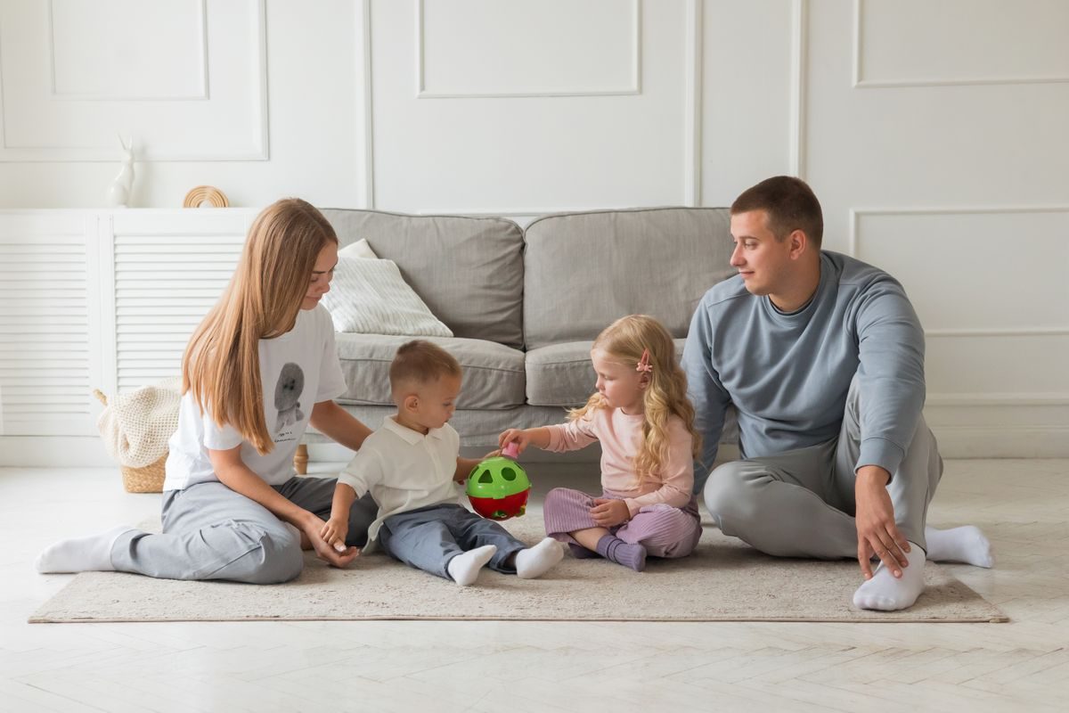 Parents playing with their two young children on the living room floor at home