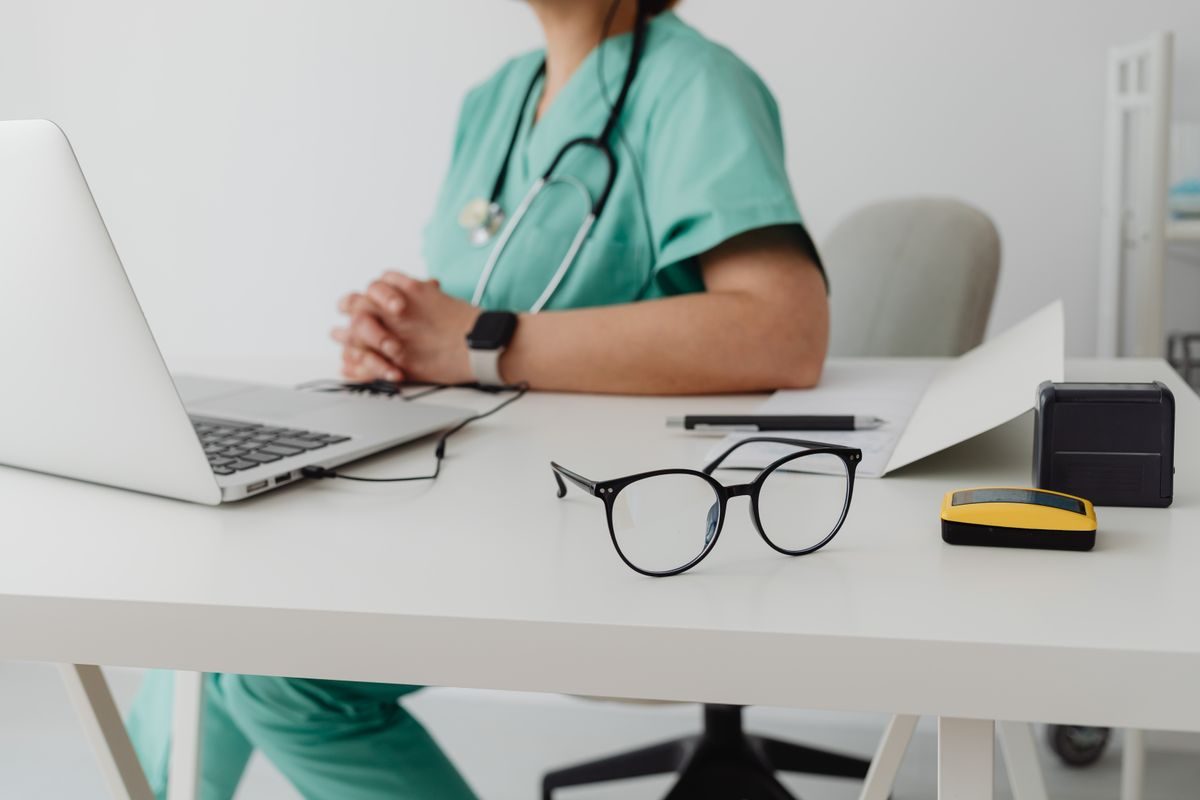 Nurse in scrubs with a stethoscope working on a laptop